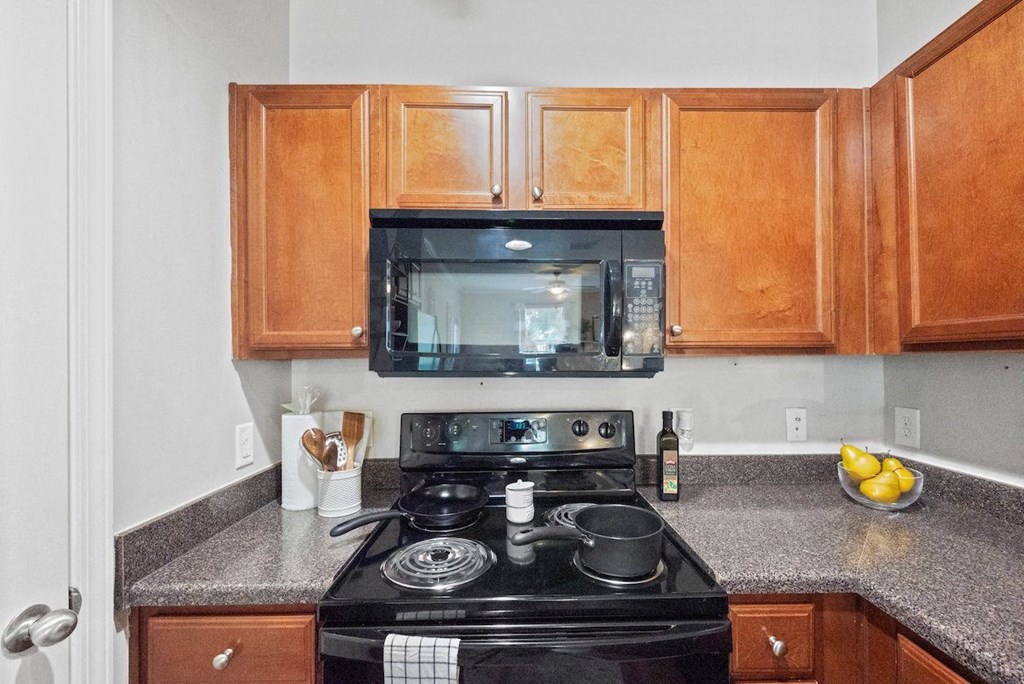 Centerville Manor's model kitchen with wood cabinets and black appliances
