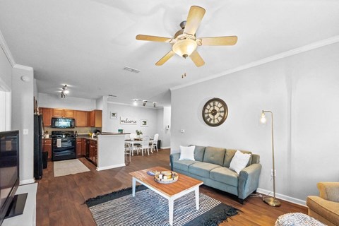 a living room with a couch and a coffee table in front of a kitchen with a stove