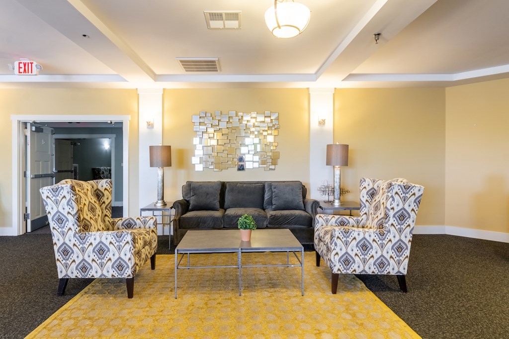 A living room with a grey couch, two chairs and a coffee table.