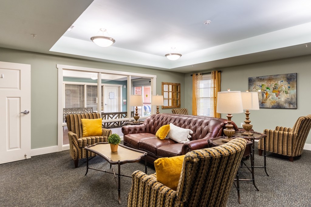 A living room with a brown leather couch and striped chairs.