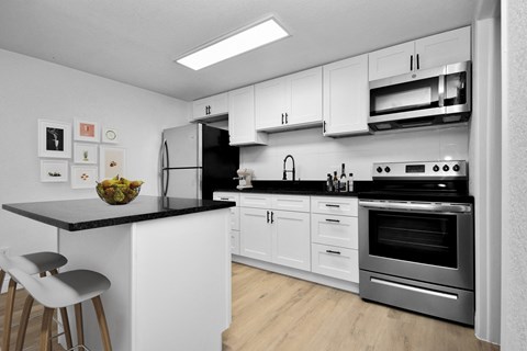 a kitchen with white cabinets and stainless steel appliances and a black counter top