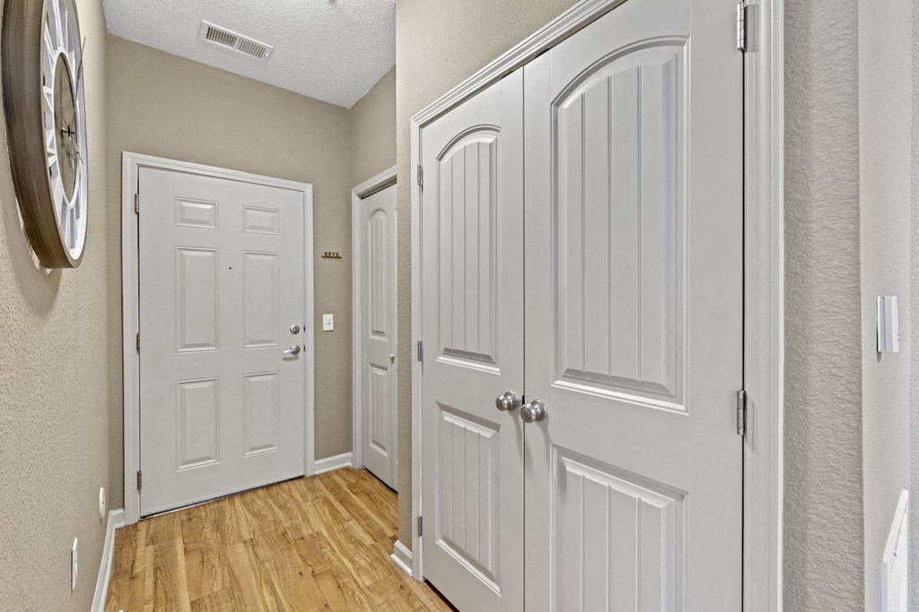a Fenwyck Manor Apartment home hallway with two doors and a clock on the wall