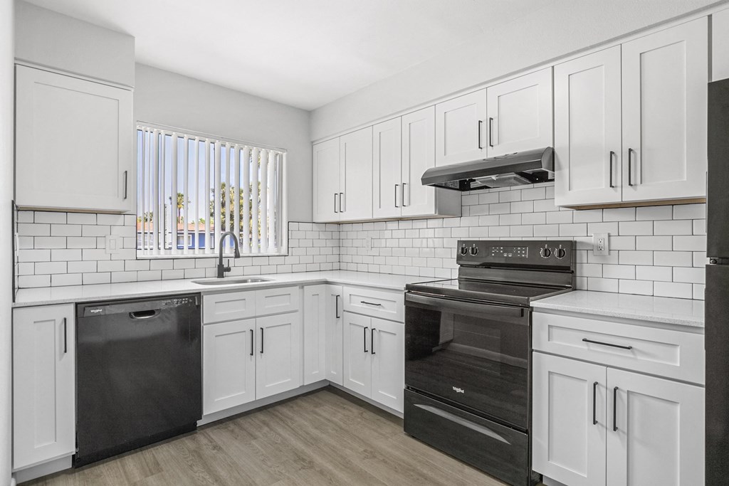 A kitchen with white cabinets and black appliances.