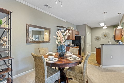 apartment dining room with a table and chairs and a kitchen in the background