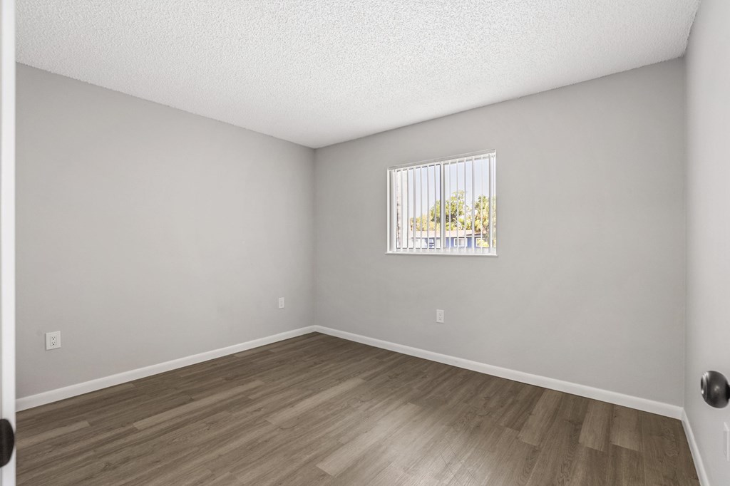 A room with a window and wooden flooring.