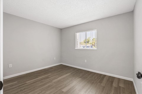 A room with a window and wooden flooring.