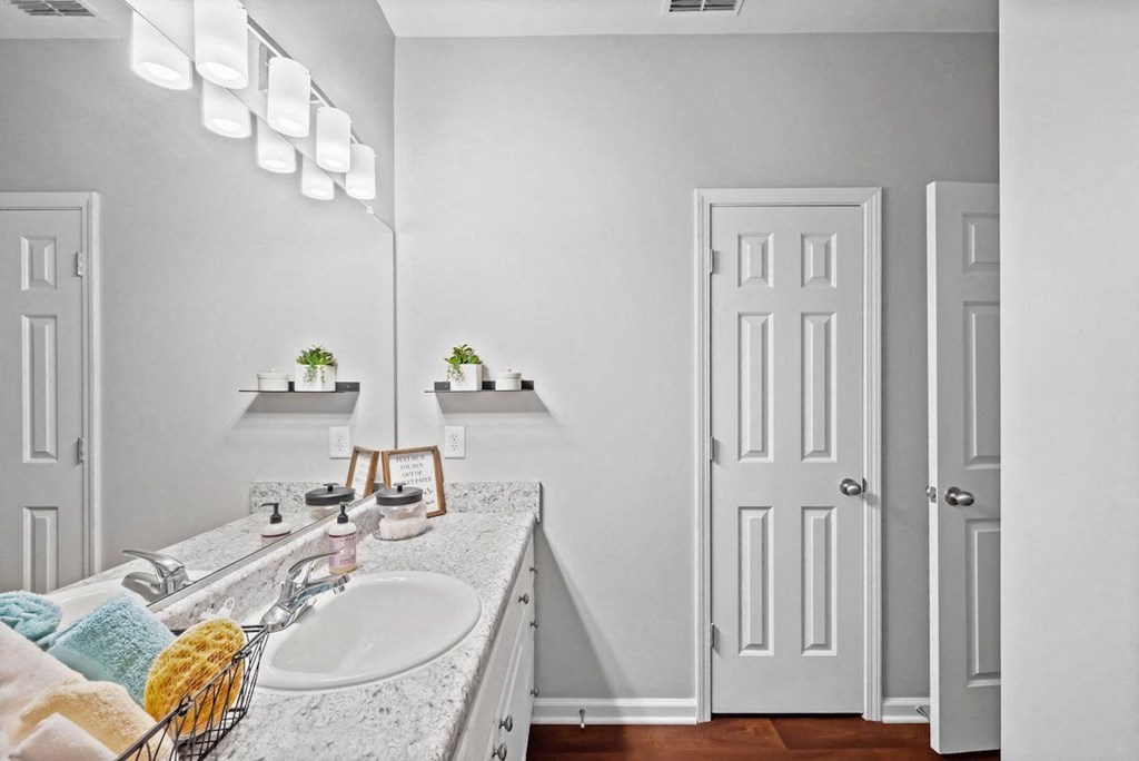 a bathroom with a sink, large vanity, and a mirror with overhead lighting