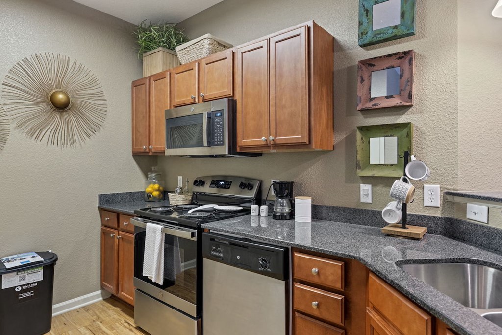 a kitchen with wood cabinets, granite countertops, and stainless steel appliances