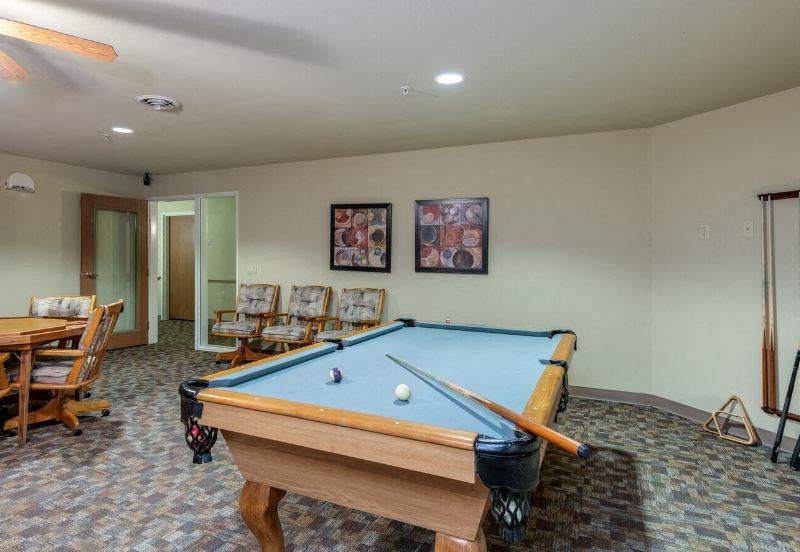 a recreational room at Harborside Commons with a pool table, game table, and seating
