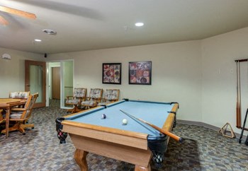 Clubhouse interior with comfortable seating, large windows, and fireplace at The Point at Fairview Apartments, Prattville, Alabama