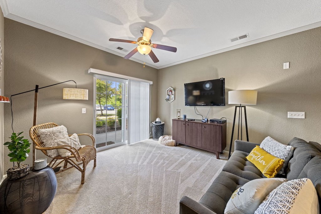large living room with sliding glass doors to deck, illuminated ceiling fan, and model decor