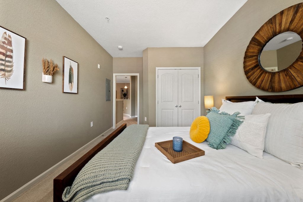 large bedroom with model furnishings, plush carpeting, and neutral paint colors