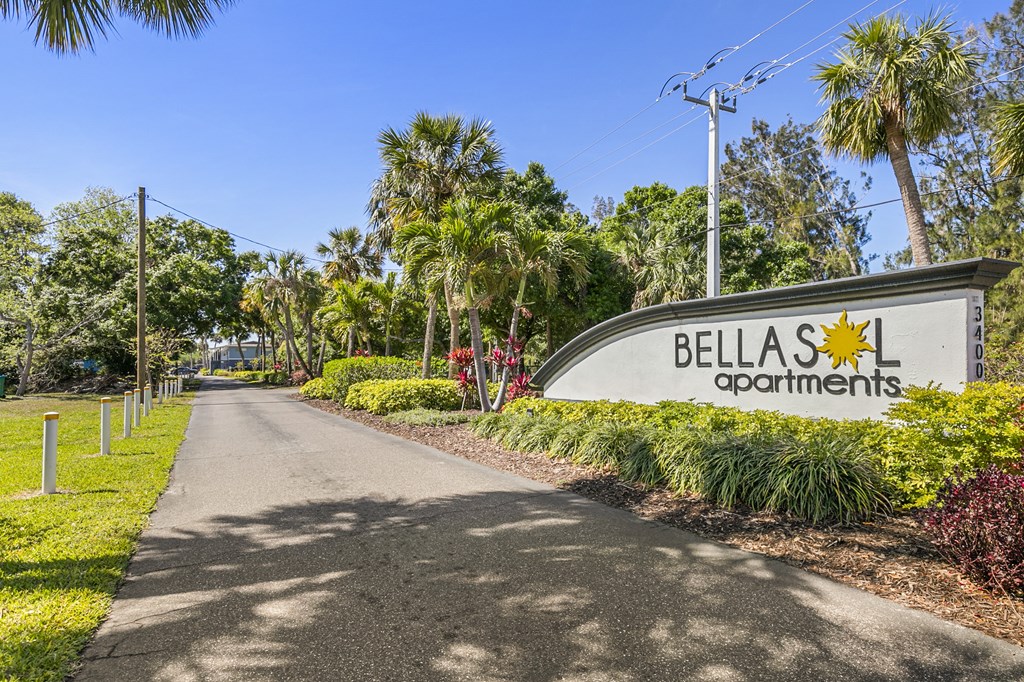 A street view of Bellas Apartments with a sign and a road.