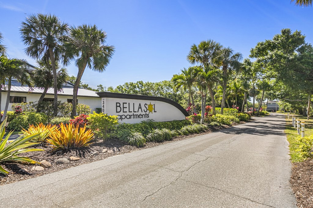 A road leading to a sign that says Bellas Apartments.