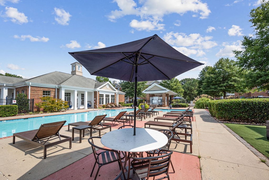 a bank of lounge chairs and tables with umbrellas by the pool at Centerville Manor Apartments
