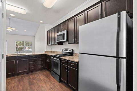 A modern kitchen with dark brown cabinets and a white refrigerator.