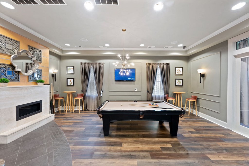 a game room with a pool table, fireplace, and a television