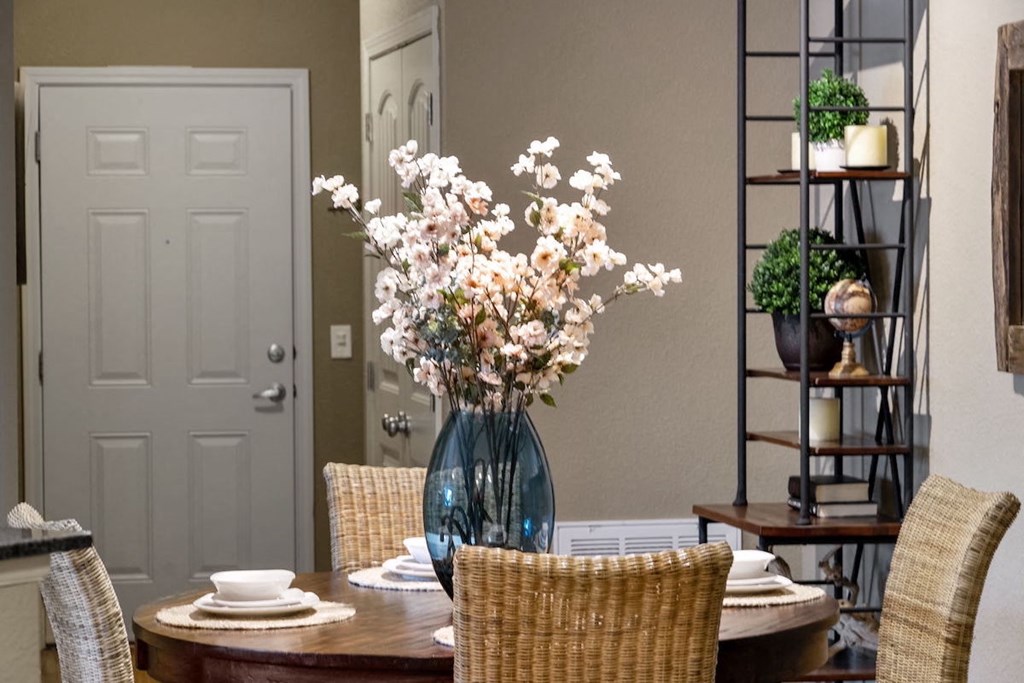 a dining room with a table and chairs and a vase of flowers in Fenwyck Manor Apartment home