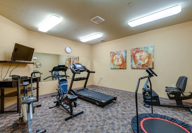 The fitness center with equipment and TV at Harborside Commons Apartments