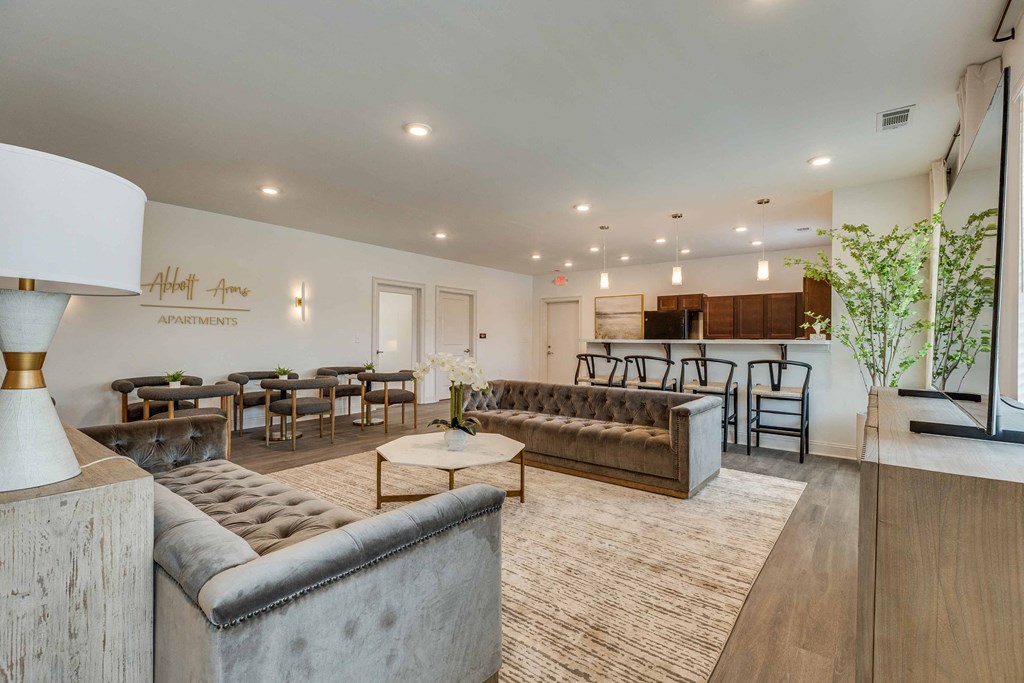 a living room with couches and tables and a kitchen