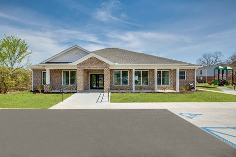 the front of a brick house with a driveway and grass