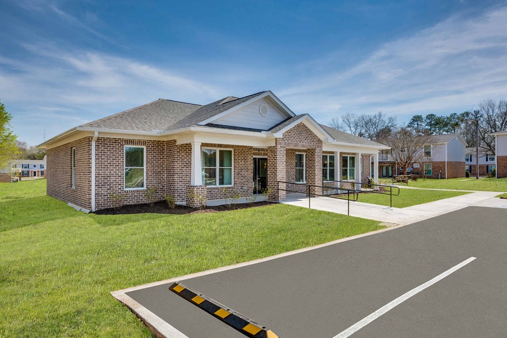 the front of a brick house with a driveway and grass