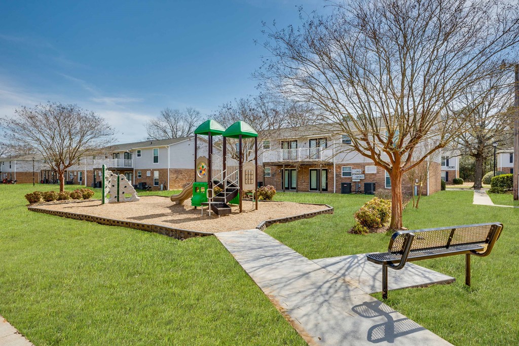 a park with a playground and benches in front of a building