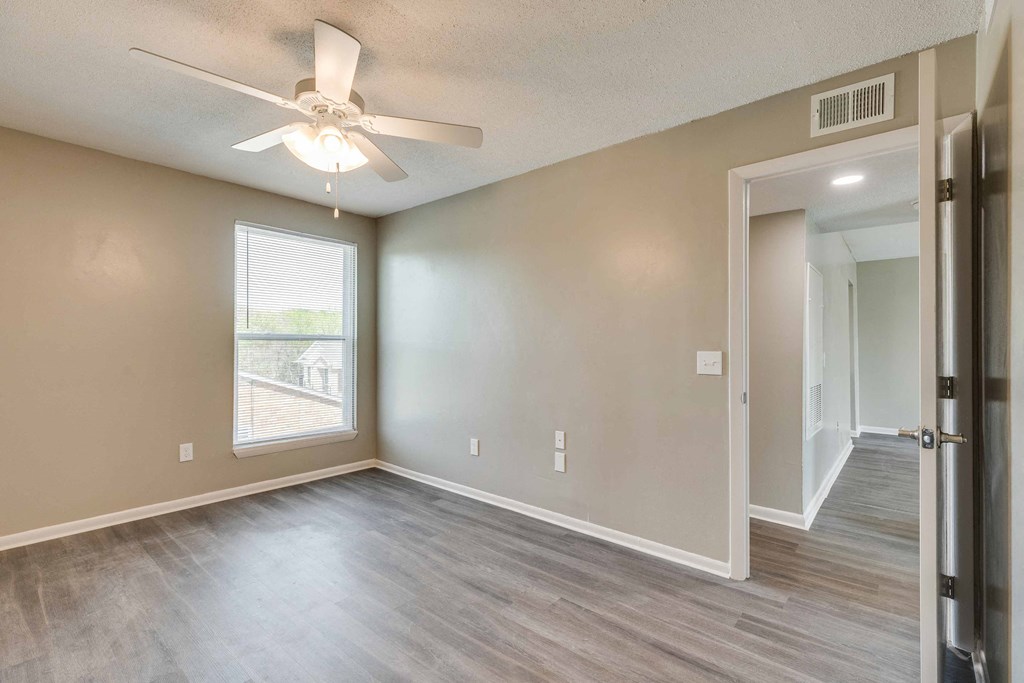 an empty living room with a ceiling fan and a window