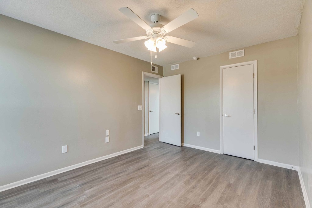 an empty living room with a ceiling fan and a door to a closet