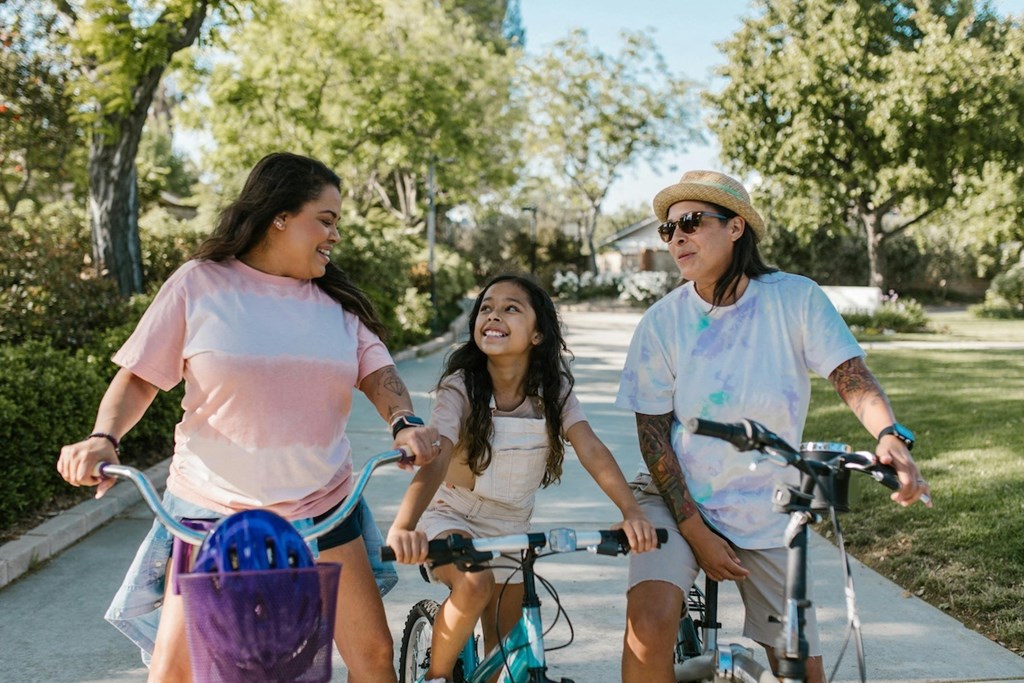 a group of women riding bikes down a sidewalk