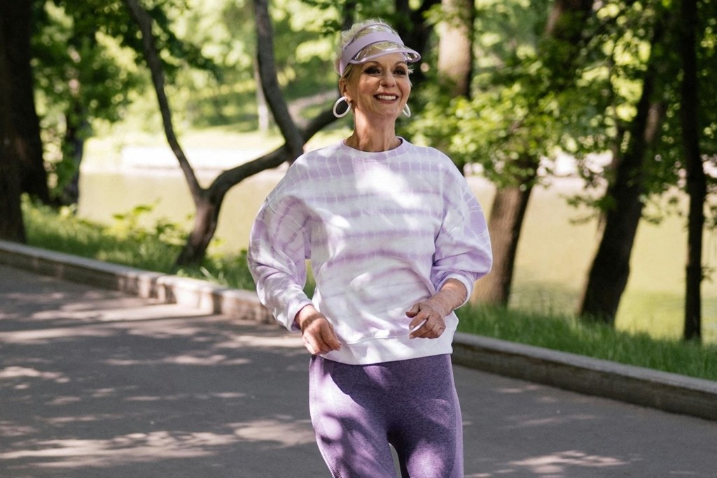 an older woman walking down a street in a park