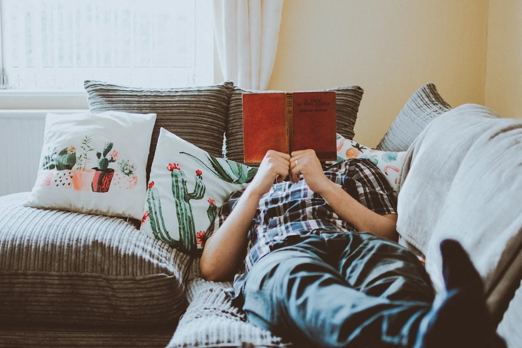 a person laying on a couch reading a book