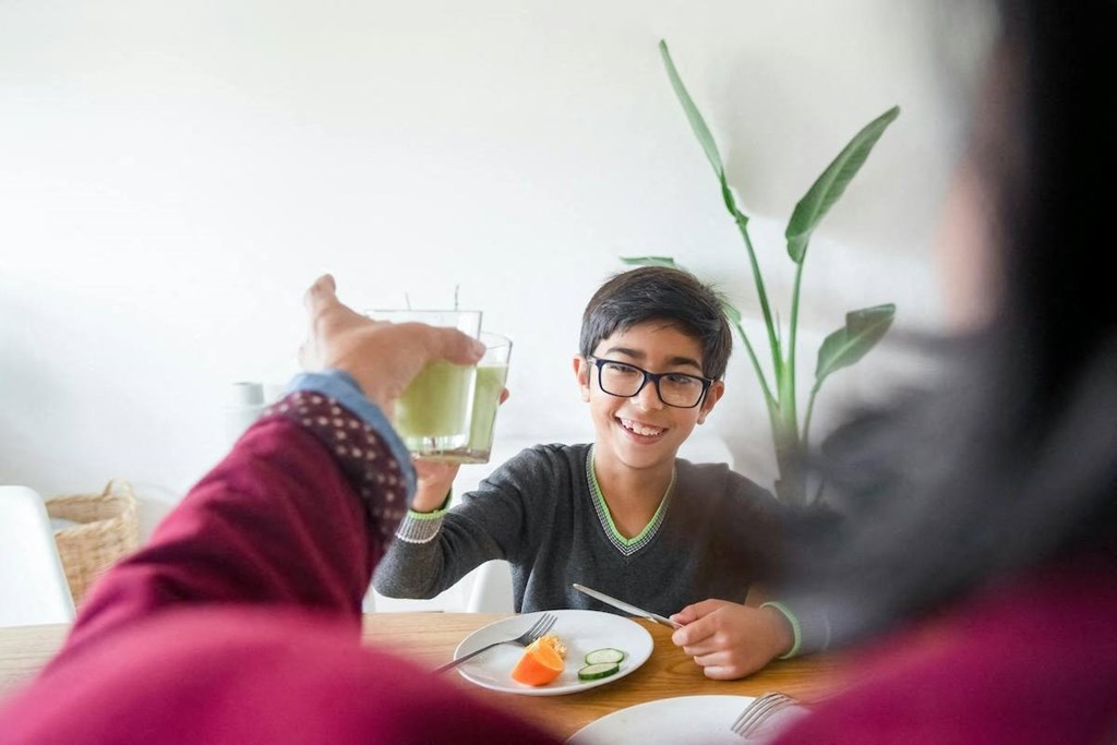 a woman giving a glass of water to a child at a table