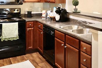 Model kitchen with black appliances and wood cabinets at Centerville Manor Apartments, Virginia