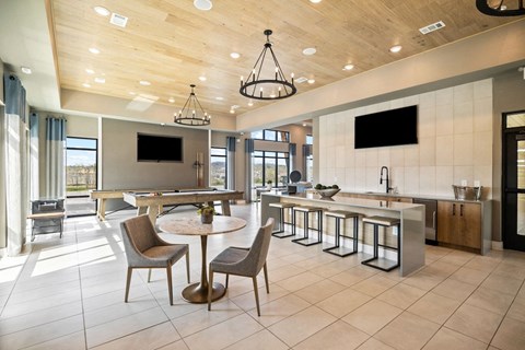 a large lobby with tables and chairs and a kitchen