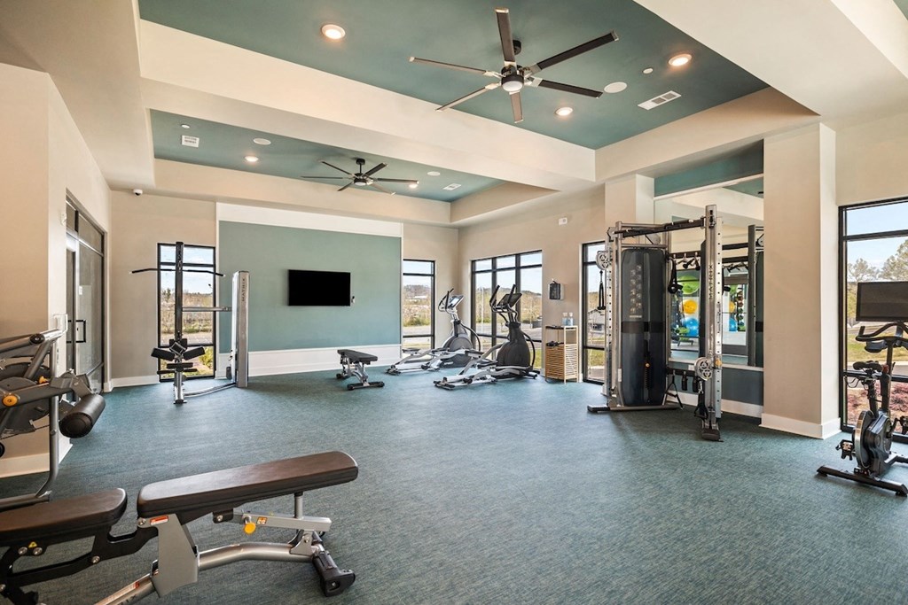 a gym with exercise equipment and a ceiling fan