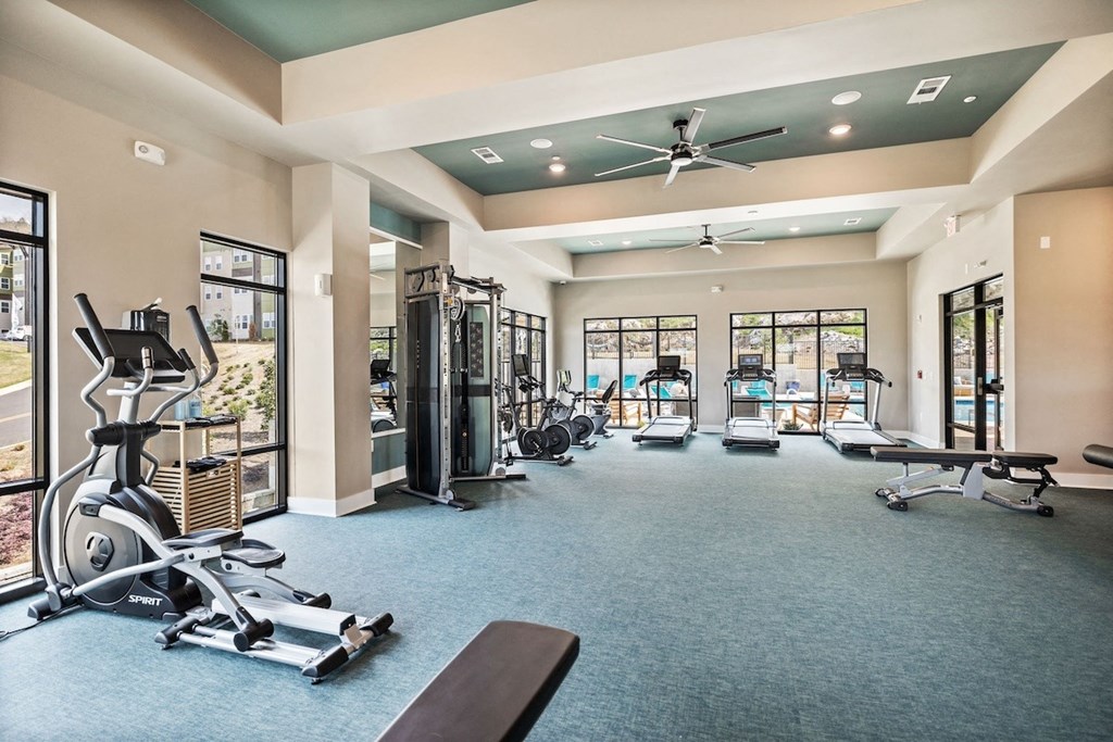 a gym with weights and cardio machines and a ceiling fan