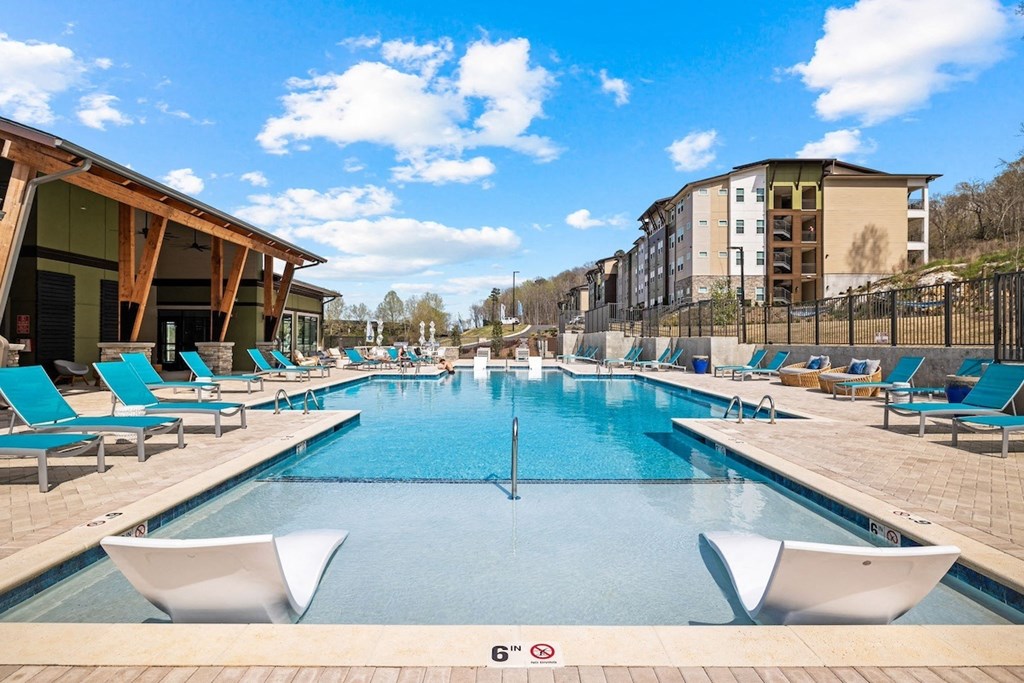 a swimming pool with blue chairs and a building in the background