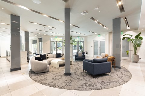 A spacious living room with a large rug and several pieces of furniture.