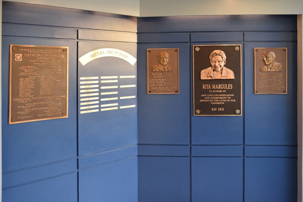a blue wall with three brass plaques on it and a plaque on the wall