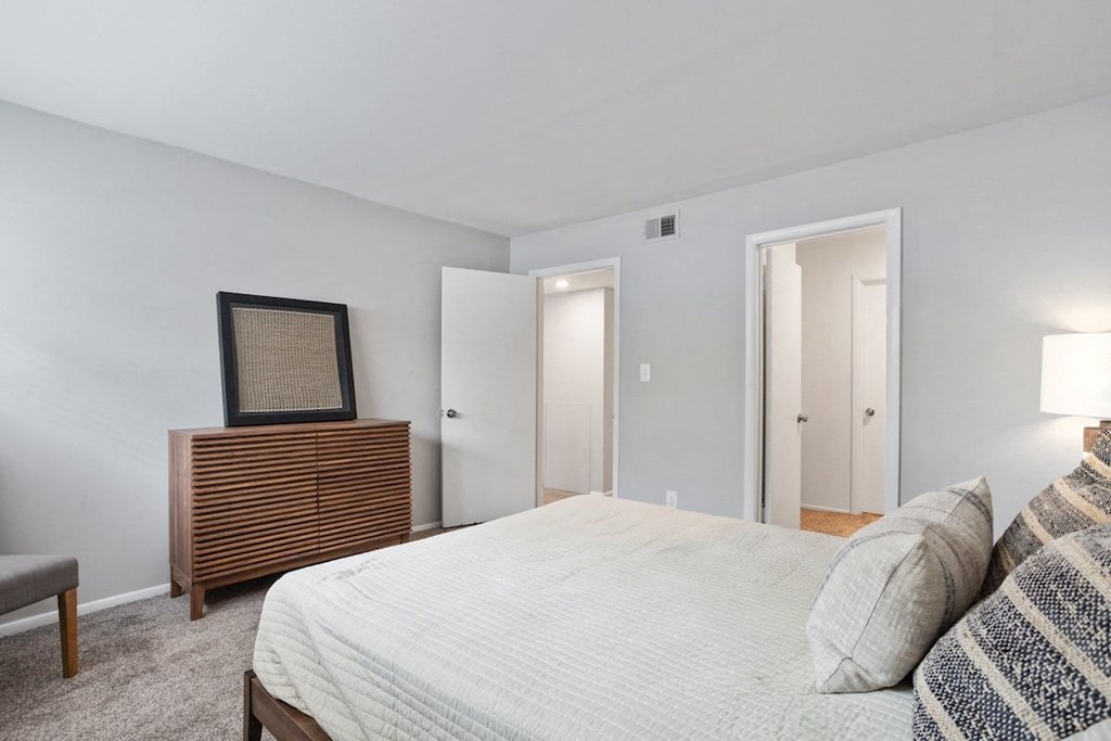 a spacious bedroom with model furnishings and plush carpeting