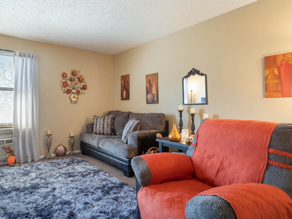 A Village Square apartment living room with a couch and a chair and a rug