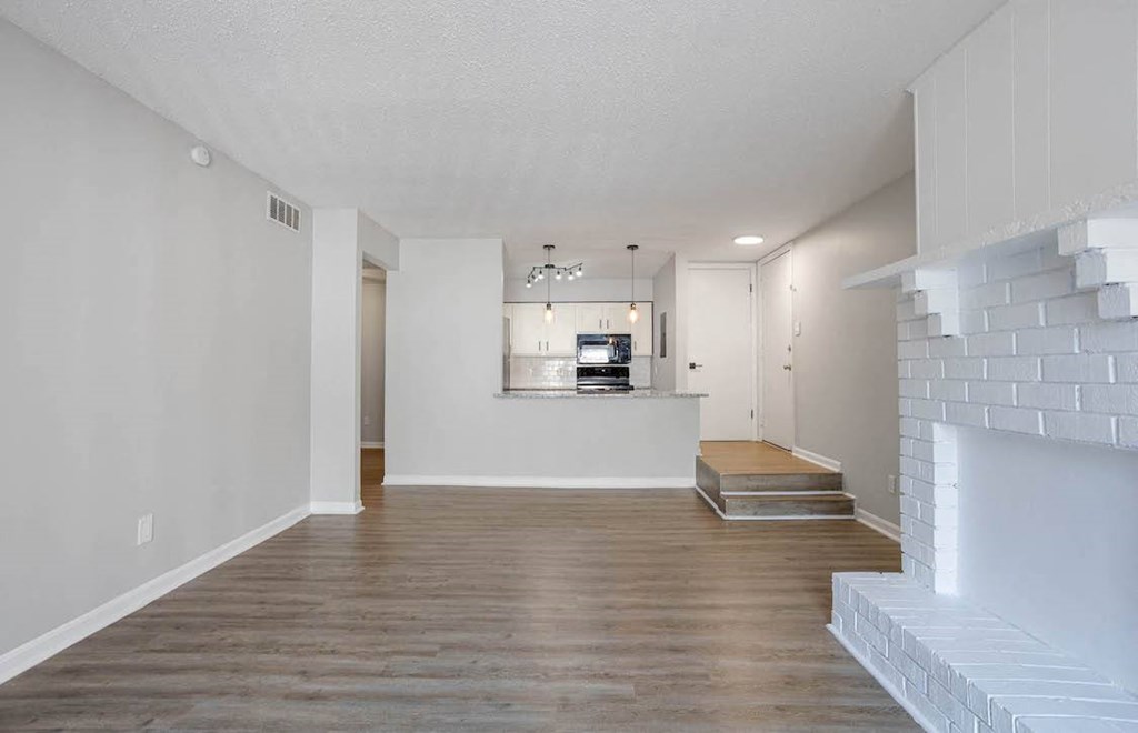 spacious living room with wood-style flooring and a cozy fireplace in apartment home at The Onyx Hoover