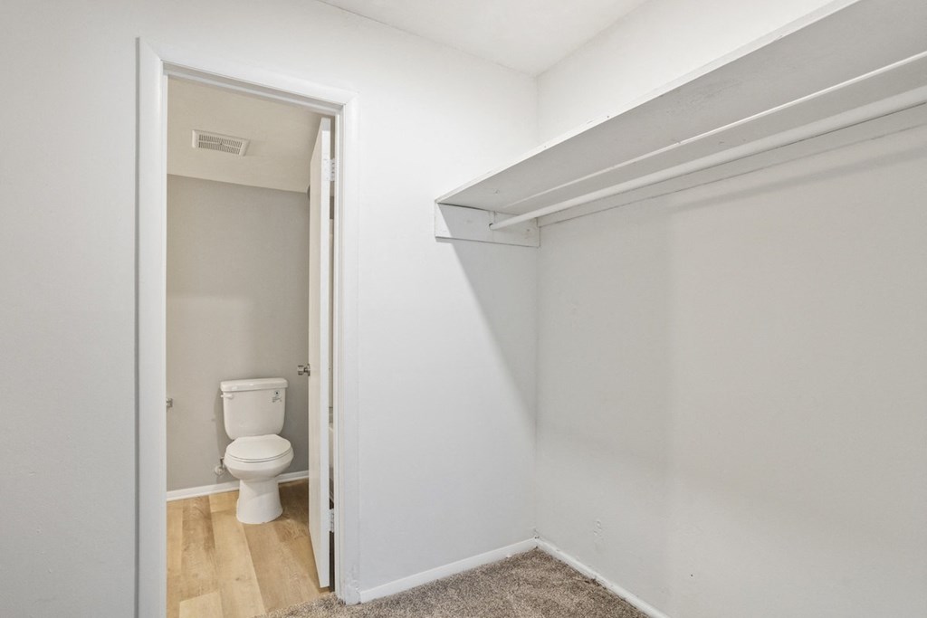 a large walk-in closet with a hanging bar and built-in shelving and bathroom access in a Mountainside Apartment