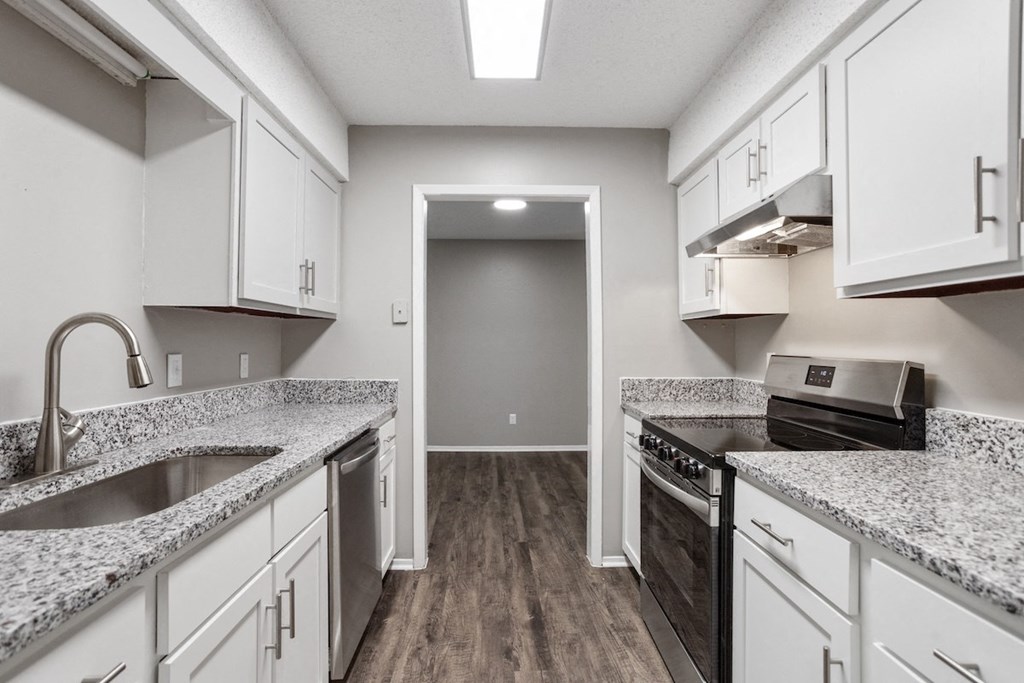 an empty kitchen with granite counter tops and white cabinets