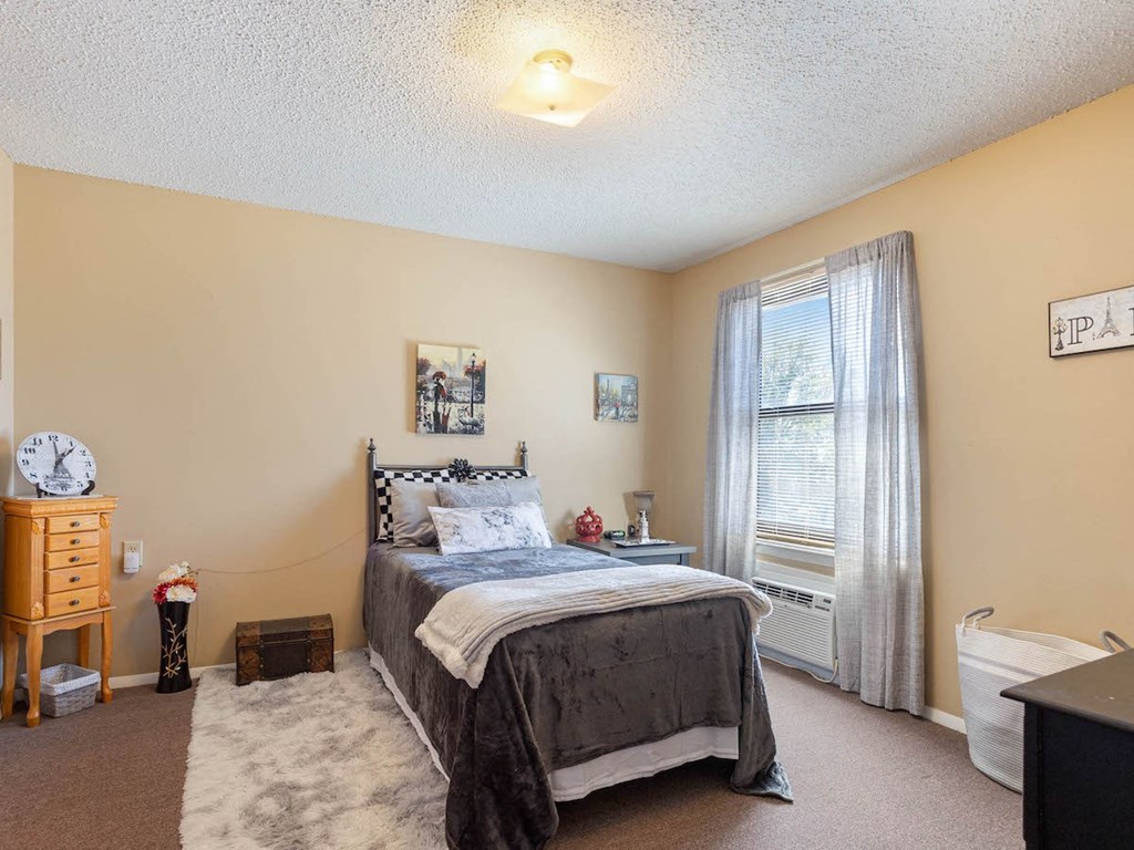 A Village Square Apartment bedroom with a bed and a window