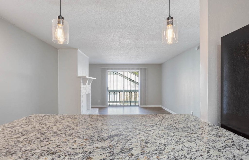 pendant lighting hanging over a quartz countertop and a living room with a fireplace and sliding glass doors