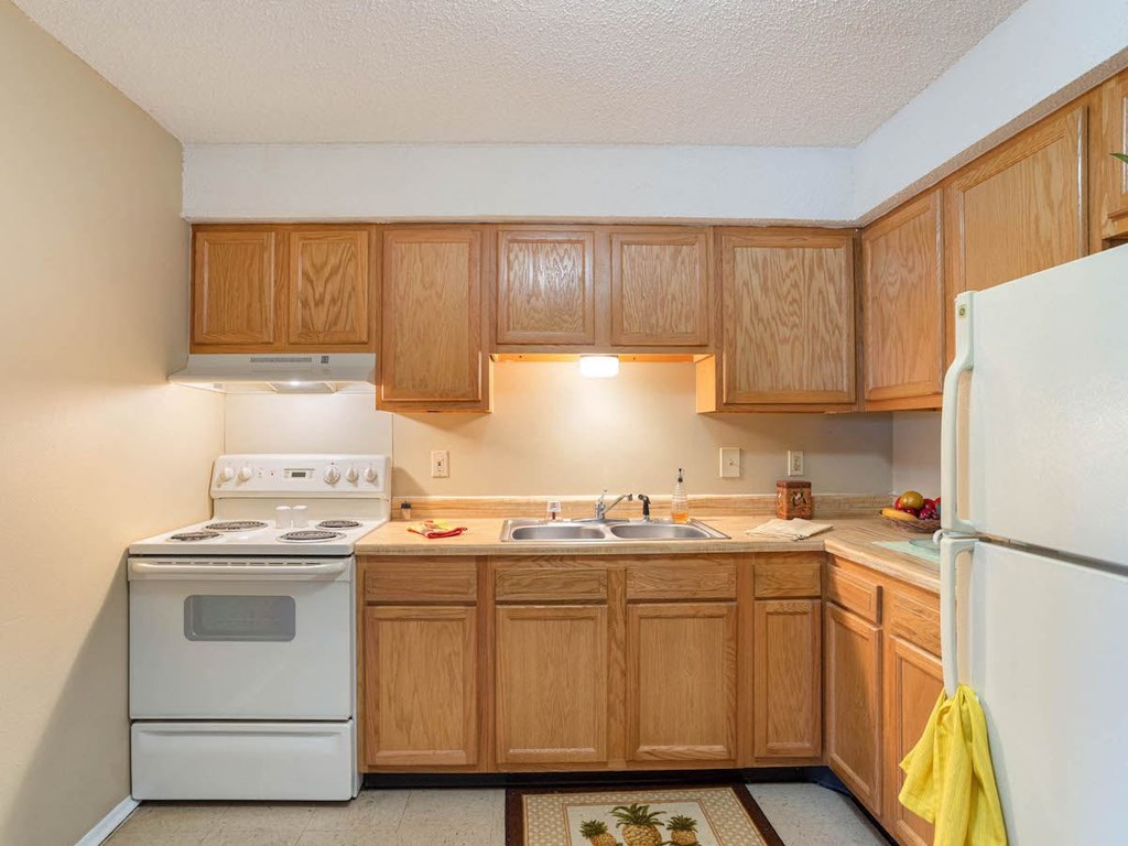 a kitchen apartment at Village Square with white appliances and wooden cabinets