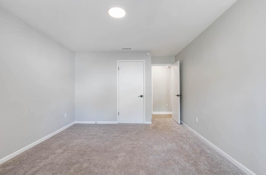 a large carpeted bedroom with overhead lighting and plush carpeting