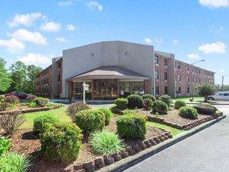 The professionally landscaped entrance to Village Square senior apartments in Russellville, AL